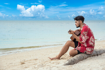 Young men playing acoustic guitar on the beach. Happy man person playing acoustic guitar music...