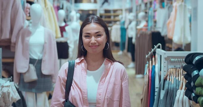 In mall's clothing store woman's smile beams into camera in close-up Woman's smile genuine expression shopping delight. Woman's smile epitome happiness sincere emotions Radiates pure joy.