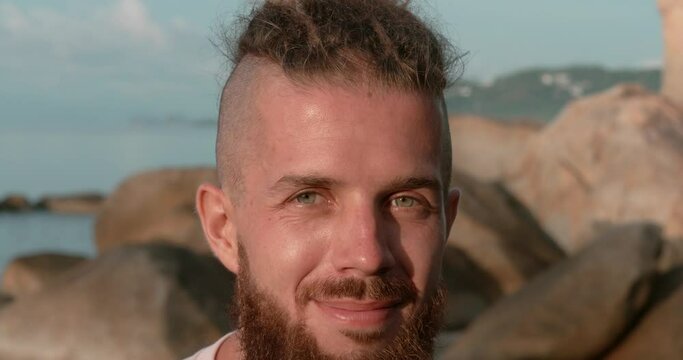 Close-up man with beard on beach during sunset sea at background Harmony in warm summer air. Harmony with oneself watching sunset Harmony essence of joyful lifestyle Embracing calm of seaside.