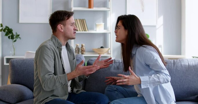 Couple conflict anger, stressed young married family couple arguing emotionally, blaming sitting on couch. Depressed husband, wife quarreling, serious relations communication problems, break up stress