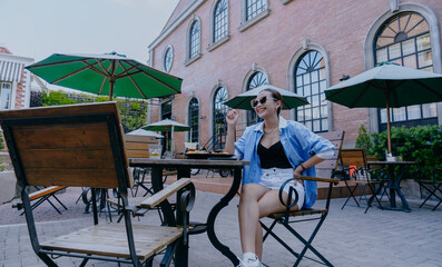 Joyful Beautiful Asian woman is sitting and eating at restaurant cafe outdoors.