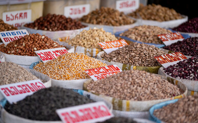 detailed view of various types of grains and legumes displayed in open bins at a market, with labels indicating names and prices, showcasing the diversity and richness of staple foods, Georgia market