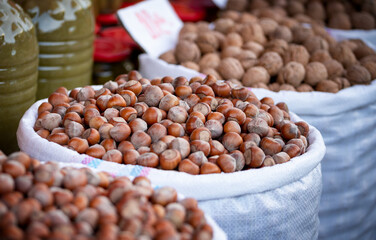 A close-up view of freshly harvested hazelnuts piled in large bags at an outdoor market, emphasizing the texture and natural appeal of these nutritious nuts.