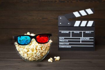 Bowl of popcorn and 3D glasses for watching movies with friends in an online cinema on a dark wood...