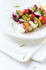 Shashlik with bacon, cherry tomato and green pepper. Bright wooden background. Close up. Copy space.	