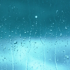 Rain drops close up on window glass outdoors. Texture of water in heavy rain. Gloomy autumn morning. Macro