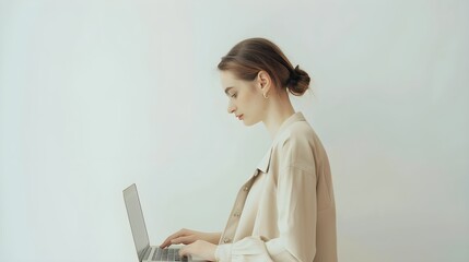 Young woman in beige clothes works using laptop computer over white wall. Aesthetic neutral pastel colors