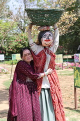 Obraz premium An Indian Lady hugging a Rajasthani Indian Scarecrow holding a basket in bright sunlight