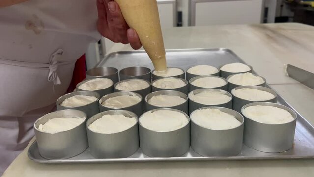 Traditional bakery scene. Baker preparing homemade cakes with a piping bag. Fixed camera. 4K 60 FPS