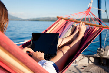 Working in traveling by sea in beach hammock. Woman with laptop on yacht. Student girl in summer...