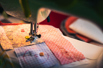 A sewing machine is in use, with a piece of fabric being sewn together