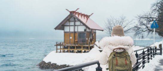 Woman tourist sightseeing Kansa Shrine and Lake Tazawa in winter. Traveler travel in Semboku city,...