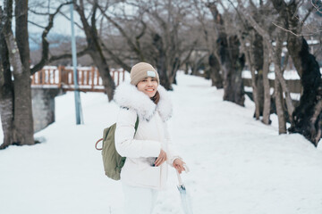 Woman tourist sightseeing sakura trees with snow. Happy traveler travel near Hinokinai River...