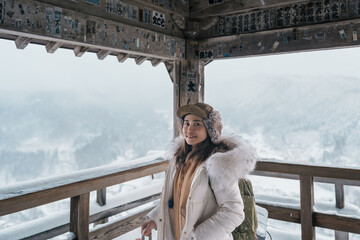 Woman tourist sightseeing view of village with snow in winter from mountain viewpoint of Yamadera...