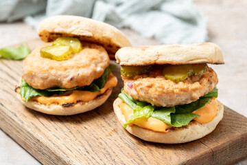 two salmon fishburgers with pickles on top