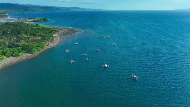 Bangka Boats on Blue Sea of Philippines during sunny day. Green Island with sandy beach in Asia. Aerial top down shot.