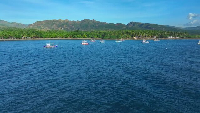 Traditional Bangka Boats on Blue Sea of Philippines during sunny day. Green Island with sandy beach in South East Asia. Aerial top down shot.