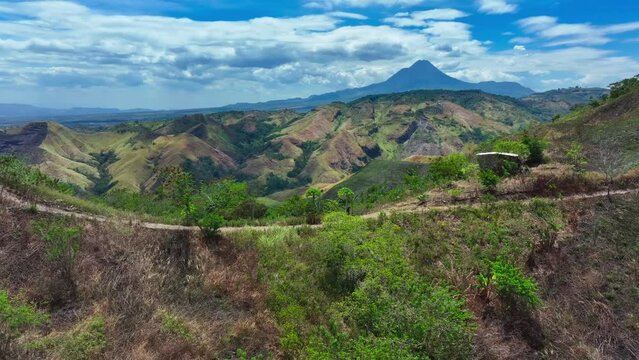 Green Lush Landscape of Philippines with road and green plants during sunny day. Large Matutum Mountain Volcano in background. Panorama view.