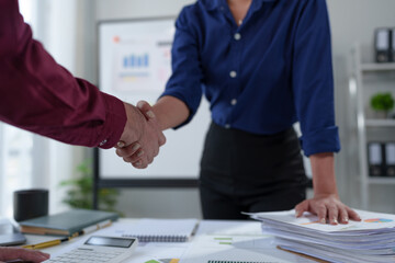 A team of businessmen, investors stand to congratulate their teammates for their successful financial performance. Striking marketing with a handshake in the office.