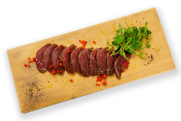 Dried meat slices on a wooden board, top view, on a white background.