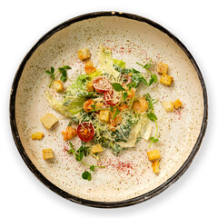 Caesar salad with shrimp on a plate, top view, on a white background.