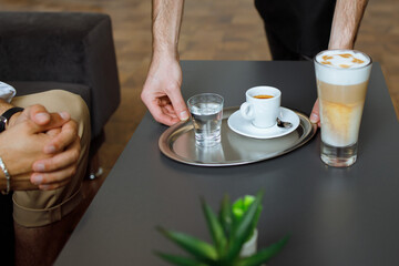 a person holding a glass of water and a cup of coffee