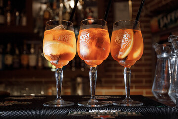 a group of glasses with orange liquid and straws