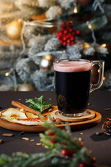 a glass mug of dark liquid with a foamy drink on a wooden plate