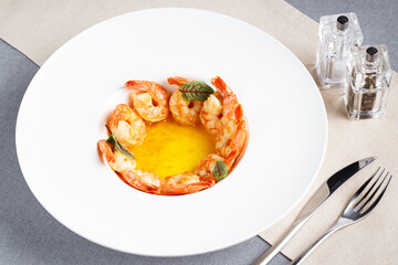 a plate of shrimp with sauce and fork and knife