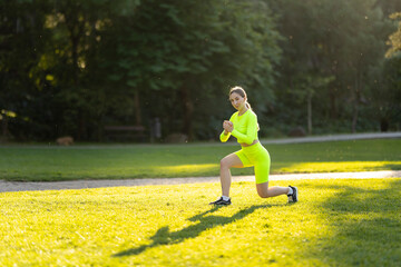 A woman in a neon green outfit is doing a yoga pose on a grassy field