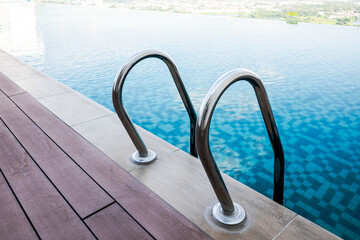 Swimming pool handrails and ladder. Blue pool water. Healthy lifestyle. Swimming sports