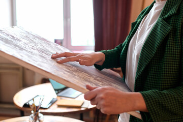 Close up of female artist holding oil painting on canvas in workshop or gallery