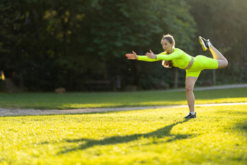 A woman is doing a yoga pose on a grassy field