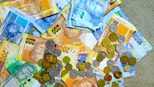 Overhead twisting view of South African rand cash banknotes and coins