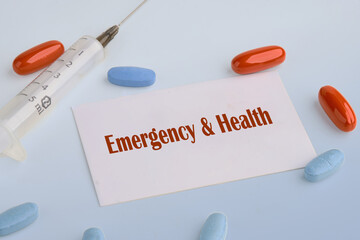 Medical concept. Emergency and Health text on a white business card on a blue background next to a syringe, pills, vitamins