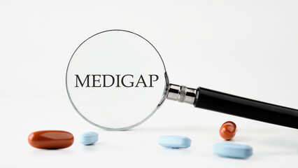 Medical concept. MEDIGAP on a white background through a magnifying glass