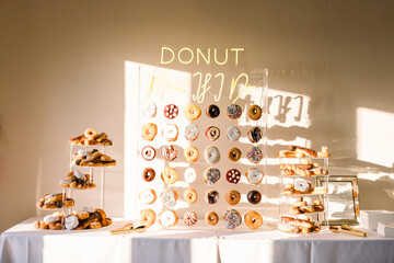 A donut wall with lots of different delicious and sweet donuts on display for a wedding reception.
