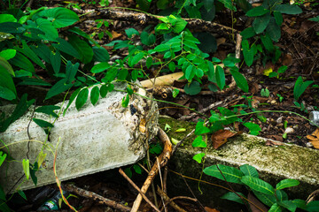 An old and damaged concrete wall on the ground is covered with dry grass