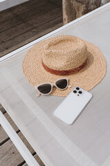 Relaxing and sunbathing concept. Straw hat, sunglasses, mobile phone on sun lounger. Summer vacation holidays at resort