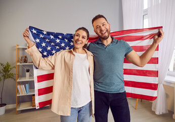 American pride and unity. Patriotic young American couple standing with iconic Stars and Stripes...