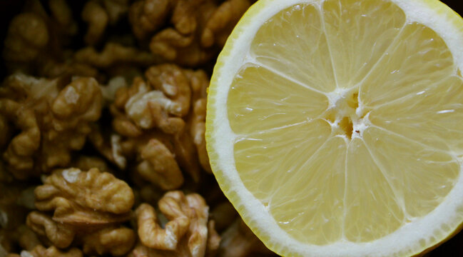 Vitamin Diet And Nutrition Background. Walnut Kernels And Sliced Juicy Lemon Fruit Closeup Stock Photo
