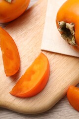 Delicious ripe persimmons on light wooden table, top view
