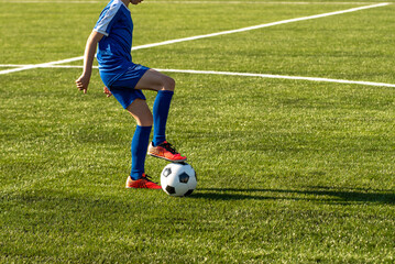 Young female soccer player kicking ball in a stadium