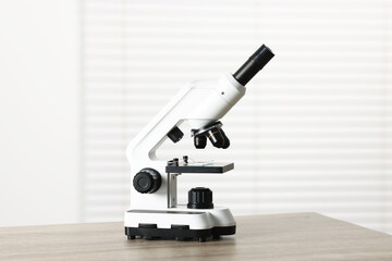 Modern medical microscope on wooden table indoors