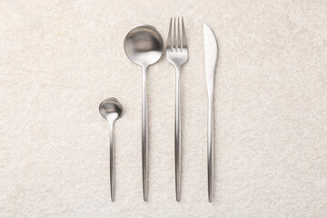 Stylish silver cutlery set on light textured table, flat lay