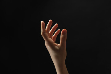 Woman holding something in hand on black background, closeup