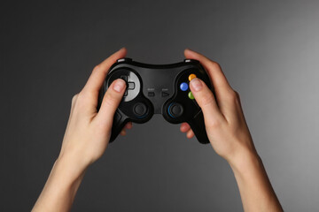 Woman with game controller on grey background, closeup