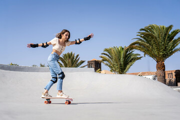 Young Woman Riding Skateboard Down Cement Ramp
