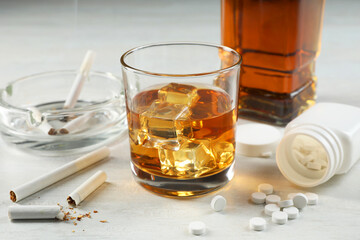 Alcohol and drug addiction. Whiskey in glass, cigarettes and pills on white table