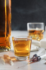 Alcohol and drug addiction. Whiskey in glass, syringes and cocaine on white table